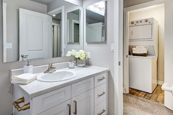 a white bathroom with a sink and mirrors